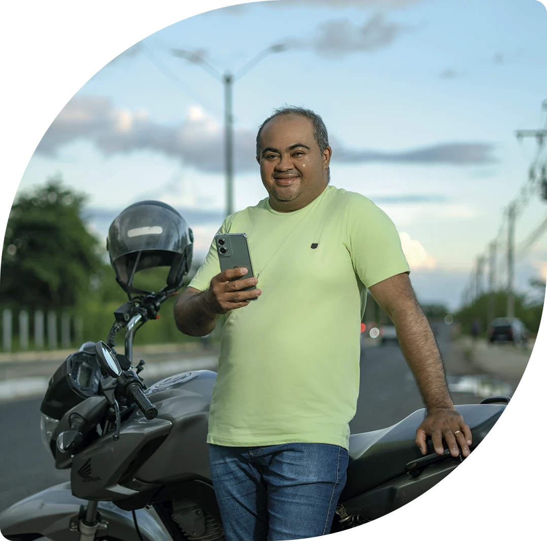 Cliente PayJoy com seu novo celular ao lado da moto